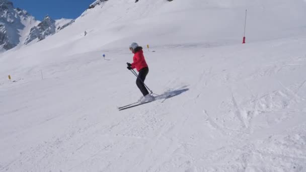 Deportiva mujer esquís tallado por la ladera en las montañas estación de esquí en invierno — Vídeo de stock