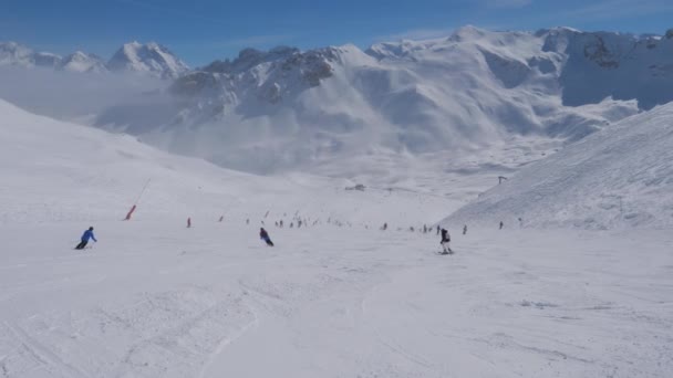 Skott av skidbacken som skidåkare gå ner i bergen på vintern — Stockvideo