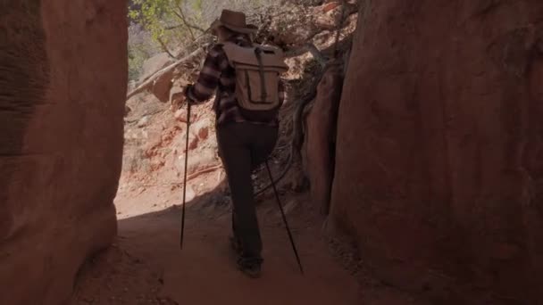 Kvinna Hiker går ut ur grottan mellan klipporna i ravinen på utsidan — Stockvideo