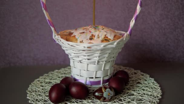 Bolo de Páscoa festivo com uma vela na cesta de vime e alguns ovos coloridos abaixo — Vídeo de Stock