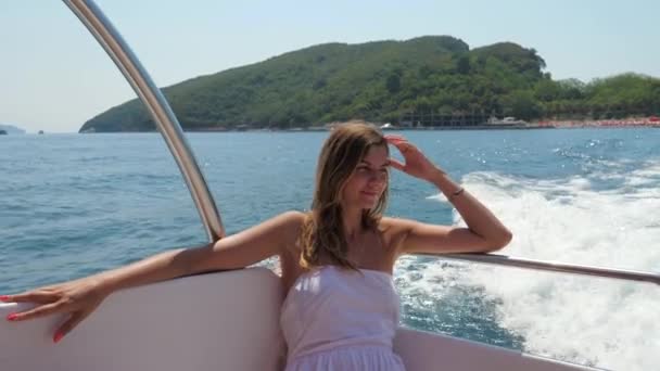Красивая молодая белая женщина в белом платье, сидящая в плавучей лодке у моря — стоковое видео