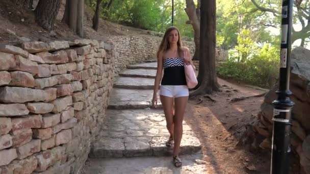 Eine schöne junge Frau spaziert durch den Park — Stockvideo