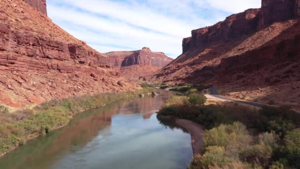 Dron leci nad rzeką Kolorado otoczony czerwoną masywną skałą w kanionie — Wideo stockowe