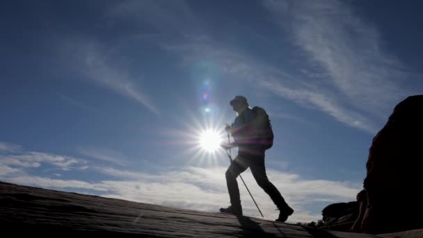 Silhouette De Randonneur Avec Un Sac à Dos Randonnée En Montée Sur Fond De Rayons De Coucher De Soleil — Video