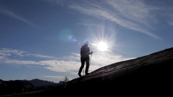 Silhouet van een toerist met een rugzak wandelen bergop achtergrond van zonsondergang — Stockvideo