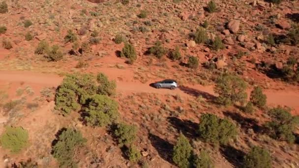 Сув їде по пилу по сільській дорозі, перетинаючи червону піщану пустелю в сонячний день — стокове відео