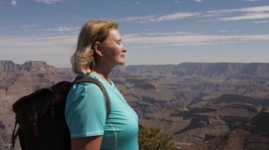 Kadın turist Grand Canyon 'un tepesinde duruyor. Temiz hava soluyor.