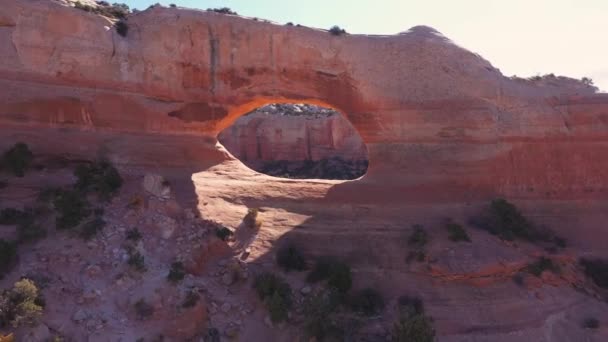 Drone vuela a través del arco de piedra roja con formaciones de roca masiva aérea — Vídeos de Stock