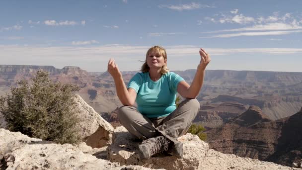 Зрелая женщина-туристка медитирует, сидя на вершине национального парка Гранд-Каньон — стоковое видео