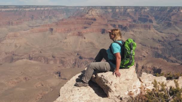 Turista senta-se à beira do Grand Canyon e admira a bela paisagem — Vídeo de Stock