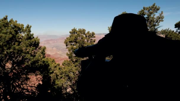 Egy turista sziluettje, aki távcsövön keresztül néz a Grand Canyonba. — Stock videók