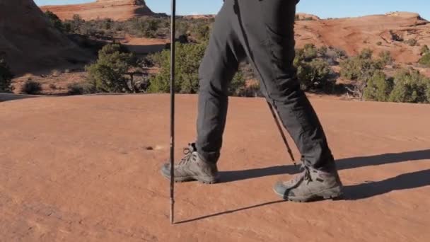 Voeten van wandelaar gaan op monolithische rots vorming oranje kleur in Arches Park — Stockvideo