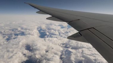 View From Window Of Aircraft On Wing And Mountain Range In Snow And Clouds