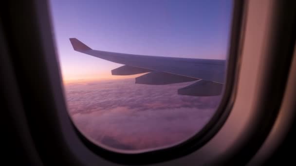 Blick auf den Flügel des Flugzeugs, das über Wolken mit scharlachrotem Sonnenuntergang fliegt — Stockvideo