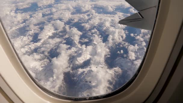 Dağdaki uçak penceresinden kar ve buzla kaplı bulutlar görünüyor. — Stok video
