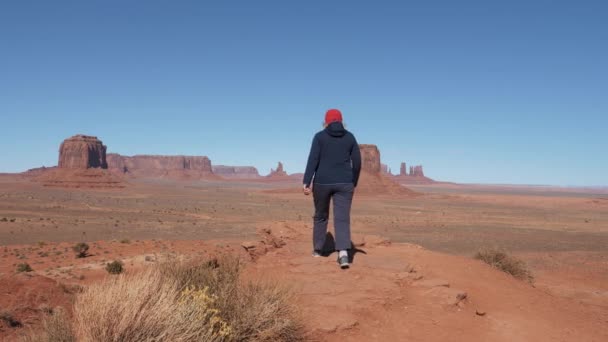 Tourist an der Spitze und hebt die Arme, um den Sieg im Monument Valley zu feiern — Stockvideo