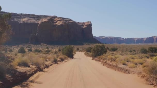 Vezetés a poros földúton a sivatagban között vörös sziklák Buttes of Monument Valley — Stock videók