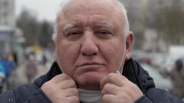 Porträtt äldre man sätter skyddande medicinsk mask på ansiktet från Coronavirus — Stockvideo