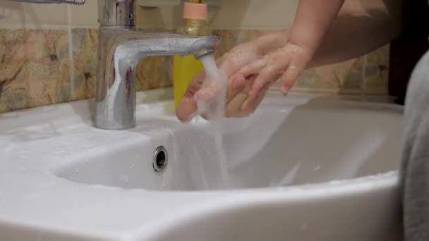 Mor tvättar sitt barn händer med vatten under kran skydd från smittat virus — Stockvideo