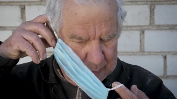 Retrato del viejo hombre caucásico usando máscara médica para proteger el virus y la enfermedad — Vídeos de Stock