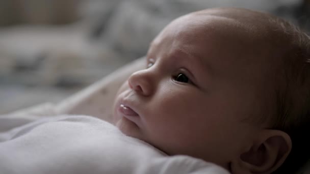 Close-up portret van vrolijke pasgeboren baby schattig pruilde zijn lippen liggend in bed — Stockvideo