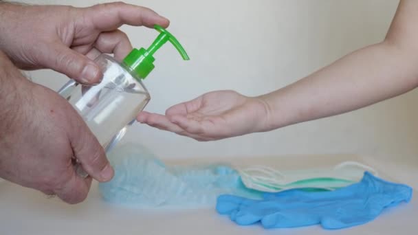 Взрослые руки сжимают антисептик из бутылки на детские руки — стоковое видео