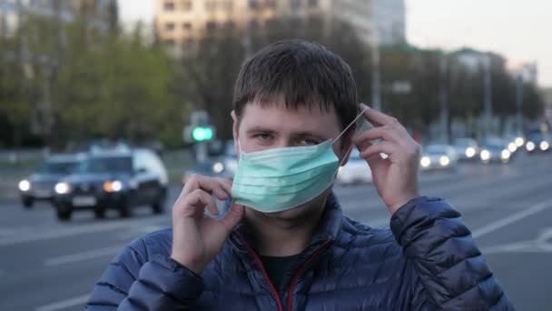 Porträtt ung man bär skyddande medicinsk mask på ansiktet på stadens gator — Stockvideo