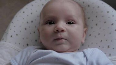 Yeni doğan çocuğun farklı yüz ifadeleri kameraya bakar ve kolları çeker