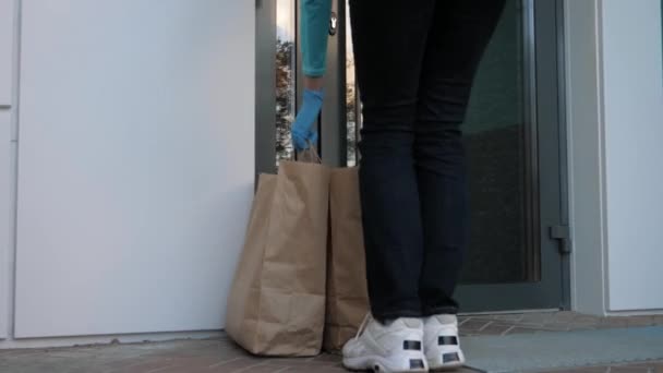 Kurir bär handskar Utför kontaktlös leverans av livsmedel till kunder Dörr — Stockvideo