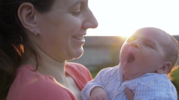 La madre acuna a su bebé recién nacido contra la puesta del sol — Vídeos de Stock