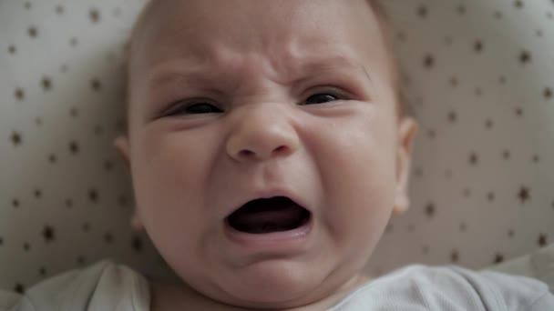 Close-up portret pasgeboren baby op bed een in een lichaam pak is huilen en schreeuwt — Stockvideo