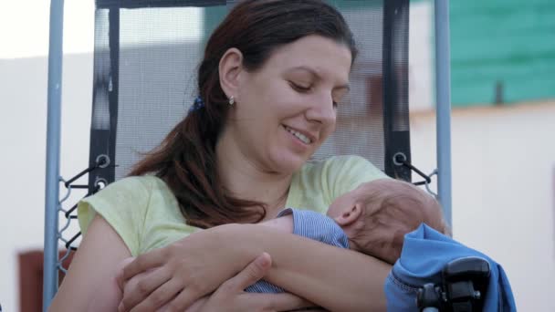 Мать поет колыбельную своему милому ребенку с любовью и убаюкивает его спать — стоковое видео