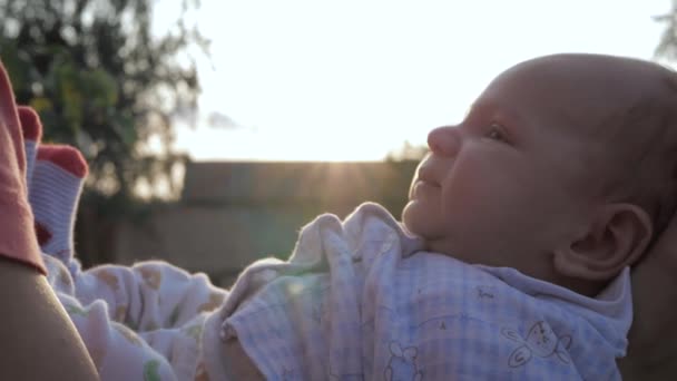 Kvinna mor håller sitt nyfödda barn i armar och kysser det mot solnedgångens strålar — Stockvideo