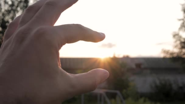 Dedos de la mano agarre sol al atardecer — Vídeo de stock