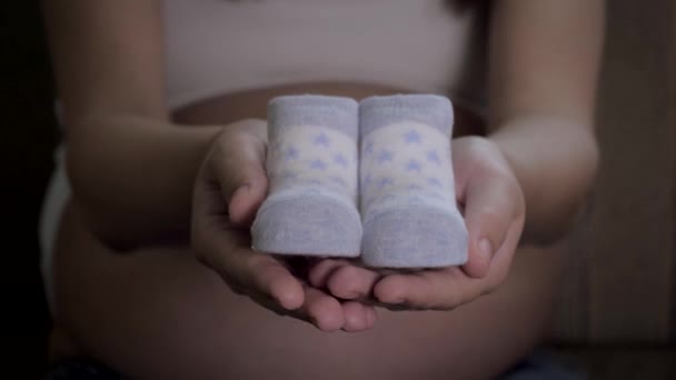 Zwangere vrouw toont haar handen mooi kleine sokken voor een pasgeboren baby close-up — Stockvideo