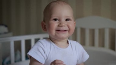 Kamera karşısında gülümseyen bebek portresi odada beşiğin arka planında