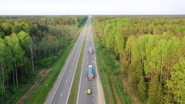 Şehirlerarası otoyolda hava görüntülü kamyonlar büyük yük taşıyor.