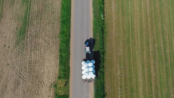 Tractor aéreo que lleva rollos de heno en remolque de campo a almacén — Vídeo de stock