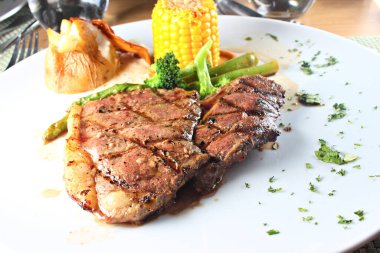 Beyaz tabakta sebzelerle servis edilen sığır filetosu bifteği.