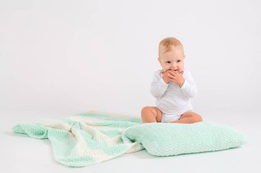 Çocuk beyaz arka planda yumuşak çizgili çift renkli battaniyeye dokunuyor.