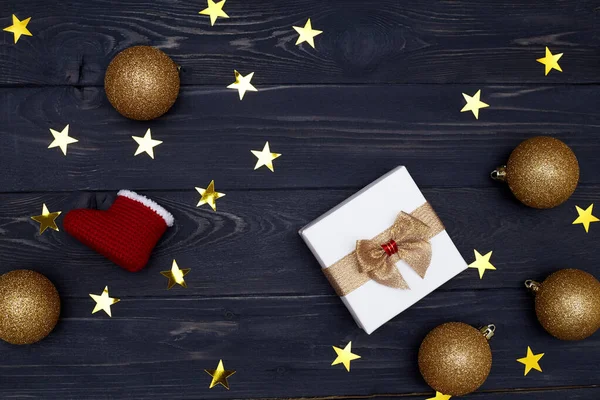 Noel Baba çizmeleri, dekorasyonlar ve siyah ahşap arka planda altın yıldızlarla çevrili hediye kutusunun üst görünümü — Stok fotoğraf