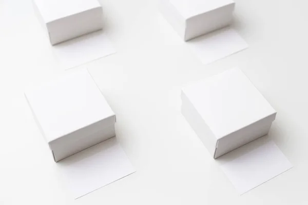 Attrappe von vier gleich großen weißen Schachteln und Visitenkarten auf weißem Hintergrund — Stockfoto