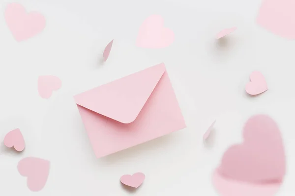 Літаючий рожевий конверт оточений літаючими рожевими серцями на білому тлі. День святого Валентина. — стокове фото