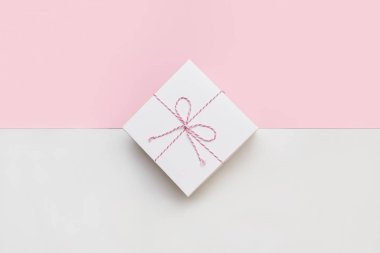 Çift renkli pembe ve beyaz arka planda pembe bir fiyonklu beyaz kağıt hediye kutusu düzeni