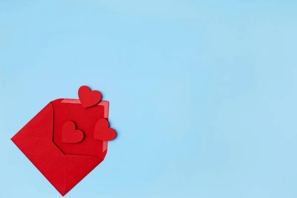 Красные сердца вылетают из красного конверта на светло-голубом фоне. Концепция поздравления на День святого Валентина — стоковое фото