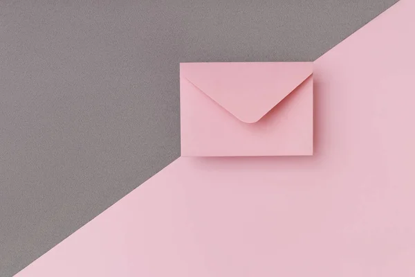 Rosa kuvert på den dubbelfärgade rosa och grå bakgrund. Postkoncept — Stockfoto