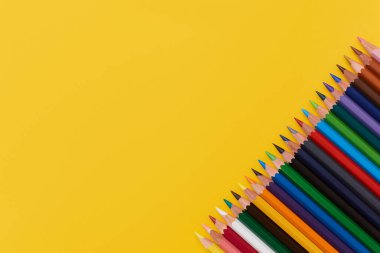 Sarı arkaplandaki çok renkli kalemlerin bileşimi