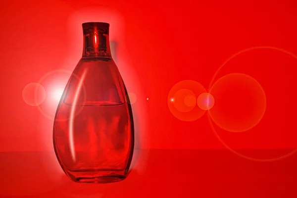 Прозора скляна пляшка з чистою рідиною на глибокому червоному тлі — стокове фото