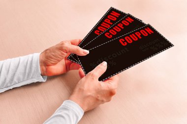 Orta yaşlı bir kadının ellerinde alışveriş için indirim kuponları.