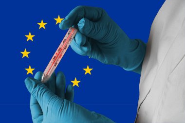 Avrupa 'da Coronavirus COVID-19 salgını. Bir doktor, Avrupa Birliği bayraklarında zatürree belirtileri olarak yüksek sıcaklıkta tıbbi termometre bulundurur.